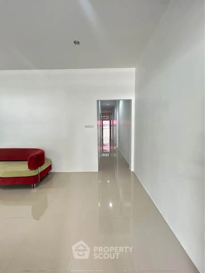 Spacious modern living room with glossy tiled floors and stylish red sofa.
