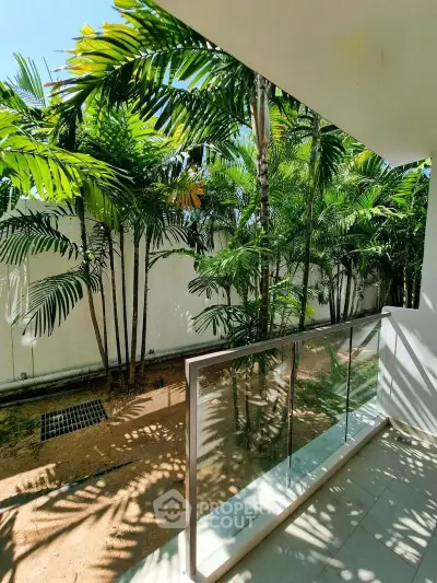 Lush garden view from modern balcony with glass railing