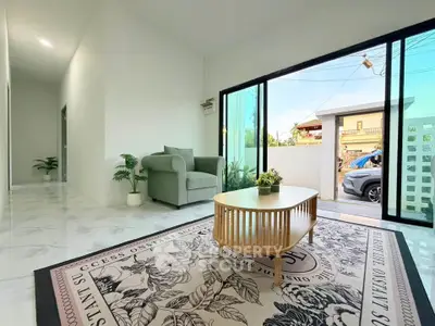 Spacious living room with modern decor and large sliding glass doors opening to a sunny outdoor area.