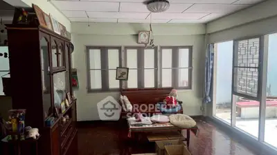 Charming living room with wooden furniture and large windows offering natural light.