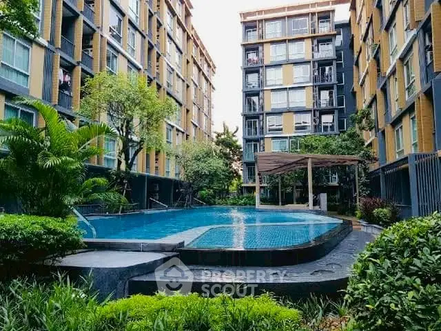 Modern apartment complex with lush greenery and inviting swimming pool.