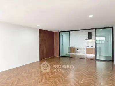 Spacious modern living room with elegant wooden flooring and open kitchen layout.