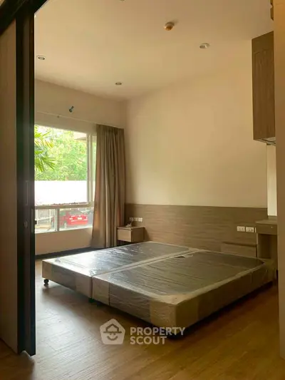 Spacious bedroom with large window and modern furnishings, perfect for natural light lovers.