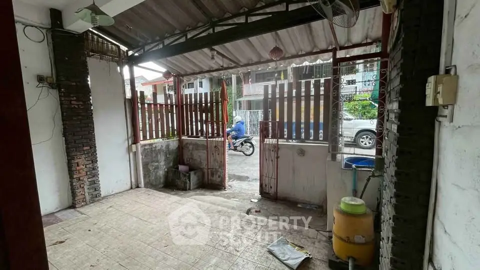 Charming covered patio with rustic gate and street view, perfect for relaxing outdoors.