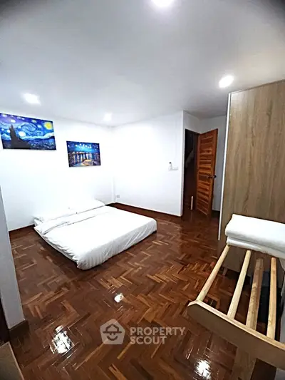 Spacious bedroom with wooden flooring and modern decor in a cozy apartment.
