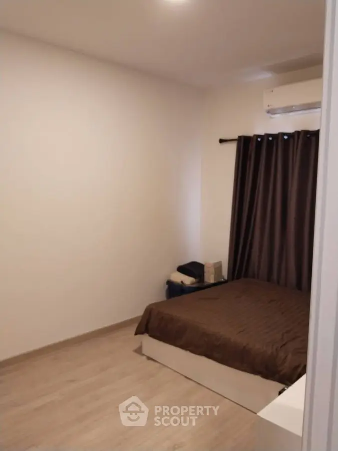 Cozy bedroom with minimalist decor and air conditioning unit, perfect for relaxation.