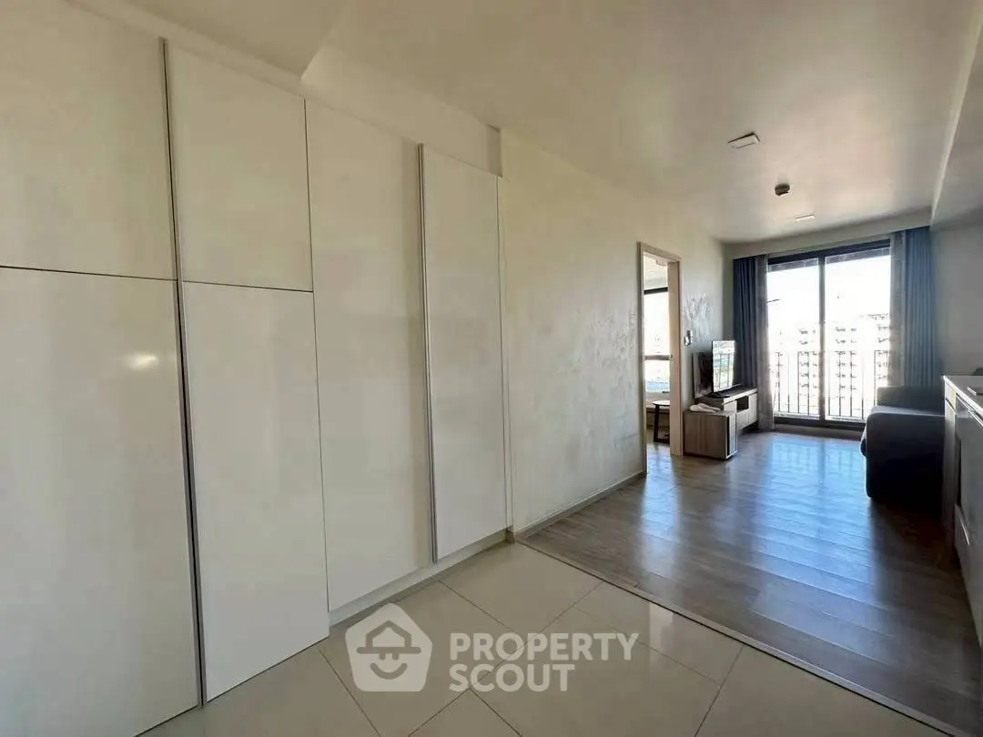 Modern apartment interior with spacious living area and large windows offering city views.