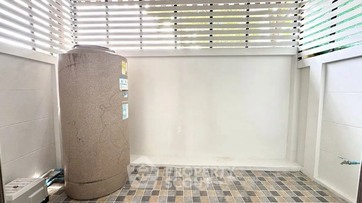 Spacious outdoor utility area with water tank and tiled flooring, perfect for storage or laundry setup.