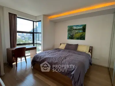 Spacious bedroom with city view and modern decor in high-rise apartment.