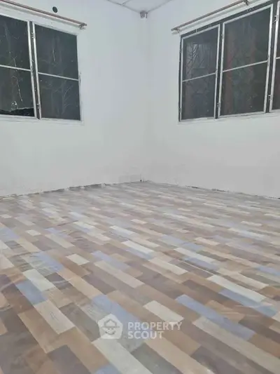 Spacious room with modern flooring and large windows for natural light.