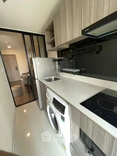 Modern kitchen with sleek appliances and washing machine in compact layout
