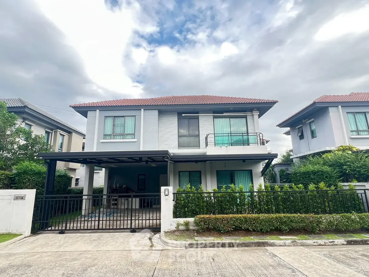 Modern two-story house with gated driveway and lush greenery