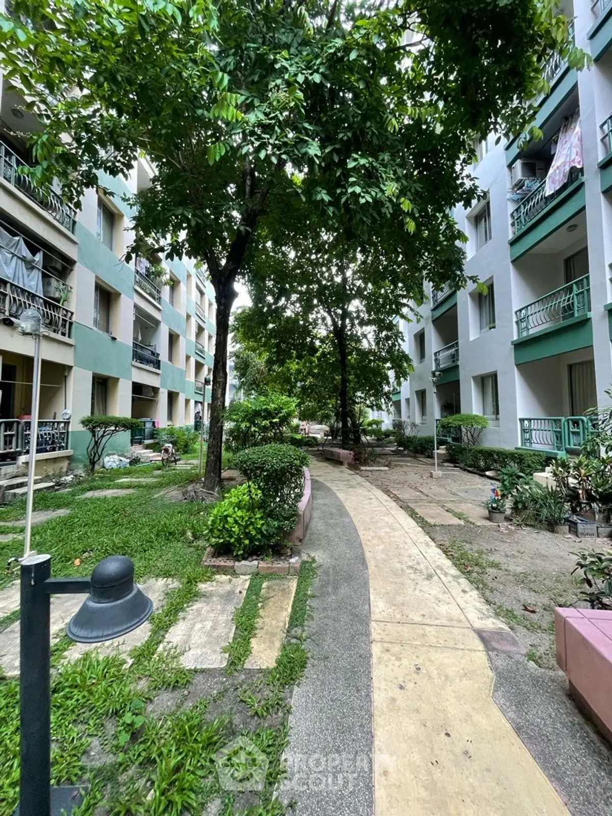 Charming residential garden path with lush greenery and apartment balconies.