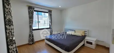 Spacious bedroom with elegant curtains and modern furnishings in a well-lit apartment.