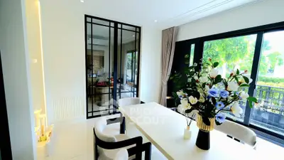 Elegant dining area with large windows and modern decor, featuring a stylish table and chairs.