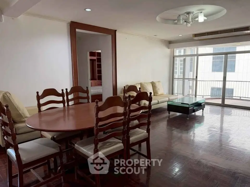 Spacious living room with elegant dining set and cozy seating area, featuring large windows for natural light.
