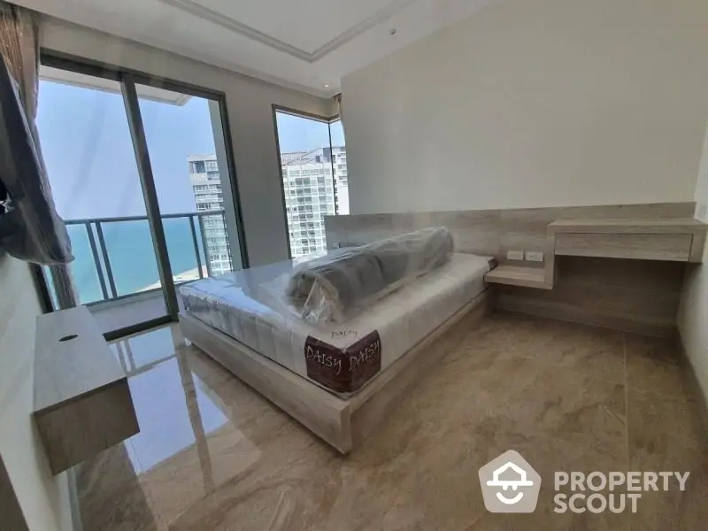 Spacious bedroom with large windows offering ample natural light and a stunning city view, featuring a modern design with sleek furniture and a polished marble floor.