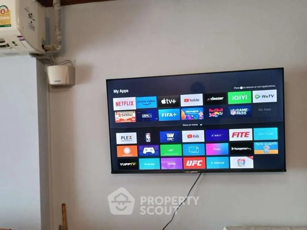 Modern living room with wall-mounted smart TV and air conditioning unit.