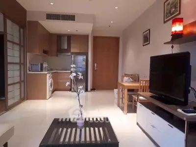Modern living room with open kitchen, featuring sleek appliances and stylish decor.