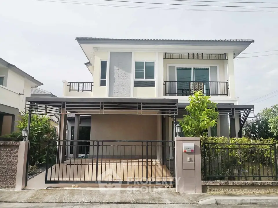 Modern two-story house with spacious balcony and gated driveway in a serene neighborhood.