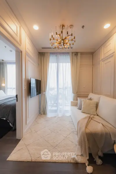 Elegant living room with chandelier and cozy decor, featuring a plush sofa and large window view.