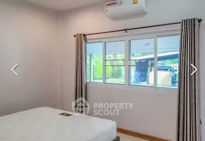 Cozy bedroom with air conditioning and large window offering natural light and garden view.