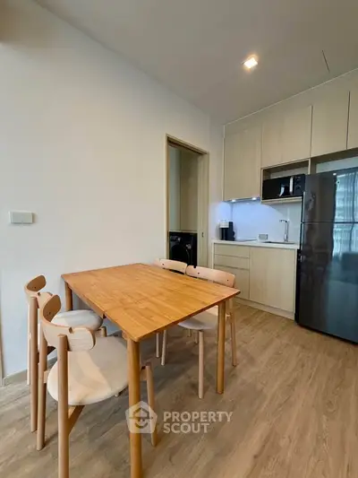 Modern kitchen with wooden dining table and chairs, sleek cabinetry, and stainless steel appliances.