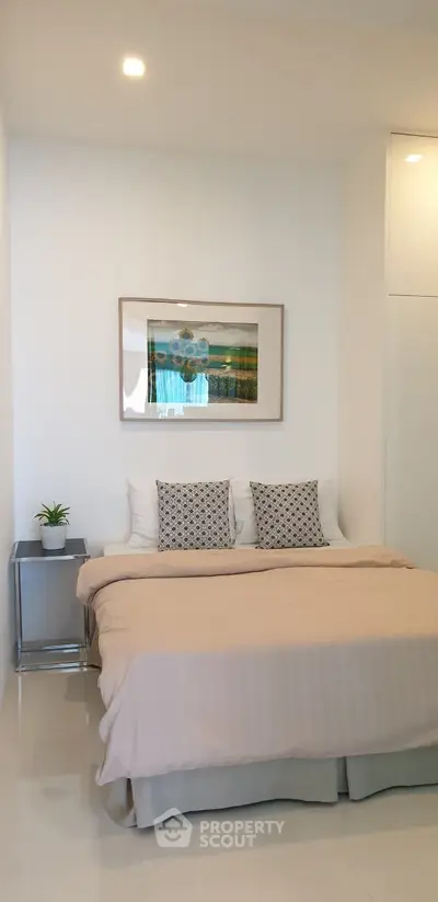 Modern bedroom with stylish decor and cozy bedding in a bright, minimalist setting.