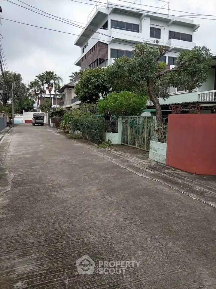 Charming residential street with modern multi-story building and lush greenery.