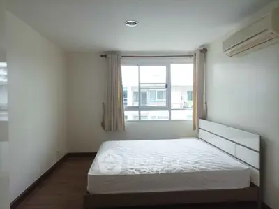 Spacious bedroom with large window and air conditioning in modern apartment.