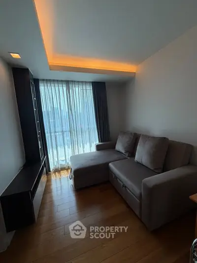 Modern living room with cozy sectional sofa and floor-to-ceiling windows offering natural light.