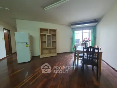 Spacious living area with wooden flooring and balcony access in modern apartment.