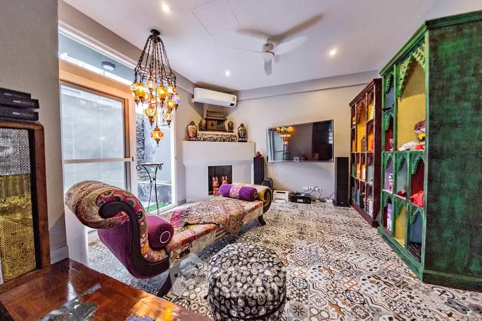 Luxurious living room with eclectic decor and vibrant colors, featuring a stylish chaise lounge and ornate lighting.