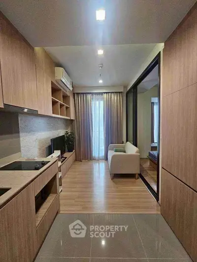 Modern open-layout kitchen and living room with wooden cabinetry and sleek design.