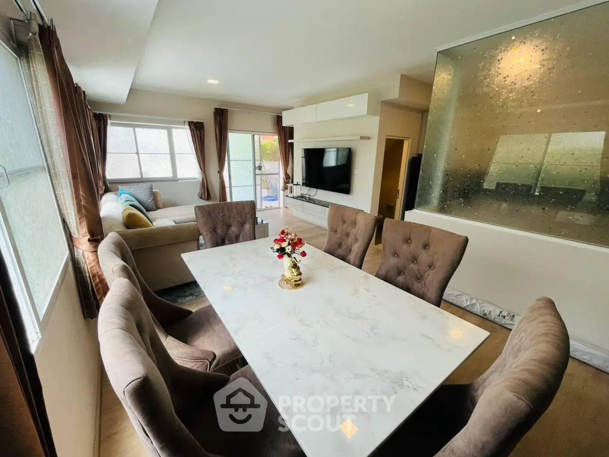 Elegant dining area with marble table and plush chairs in a modern open-plan living space.