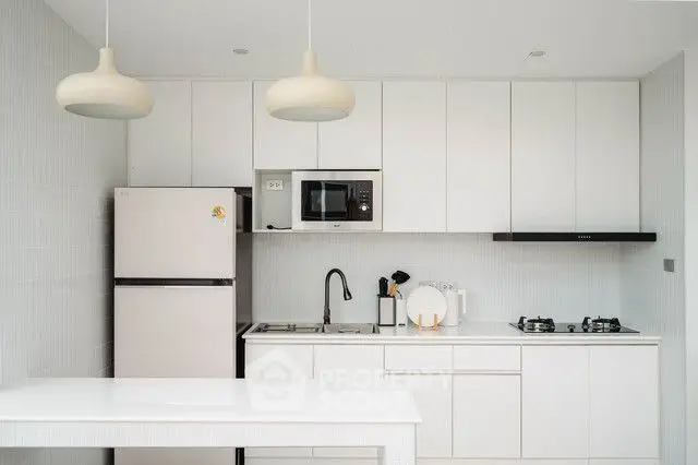 Modern kitchen with sleek white cabinets and gas stove, featuring minimalist design and ample storage.