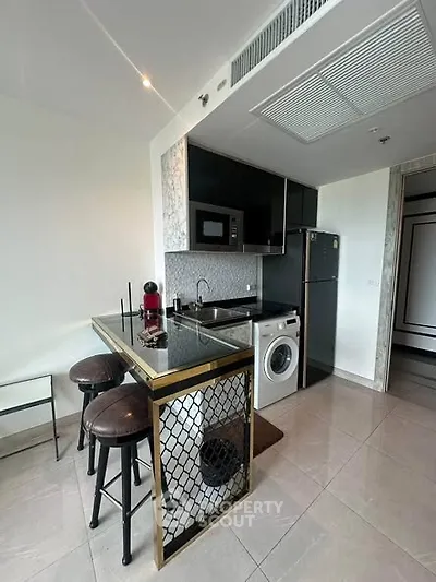 Modern kitchen with sleek black cabinets, built-in appliances, and stylish breakfast bar seating.