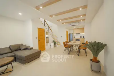Modern open-plan living room with stylish furniture and kitchen, featuring wooden accents and cozy lighting.
