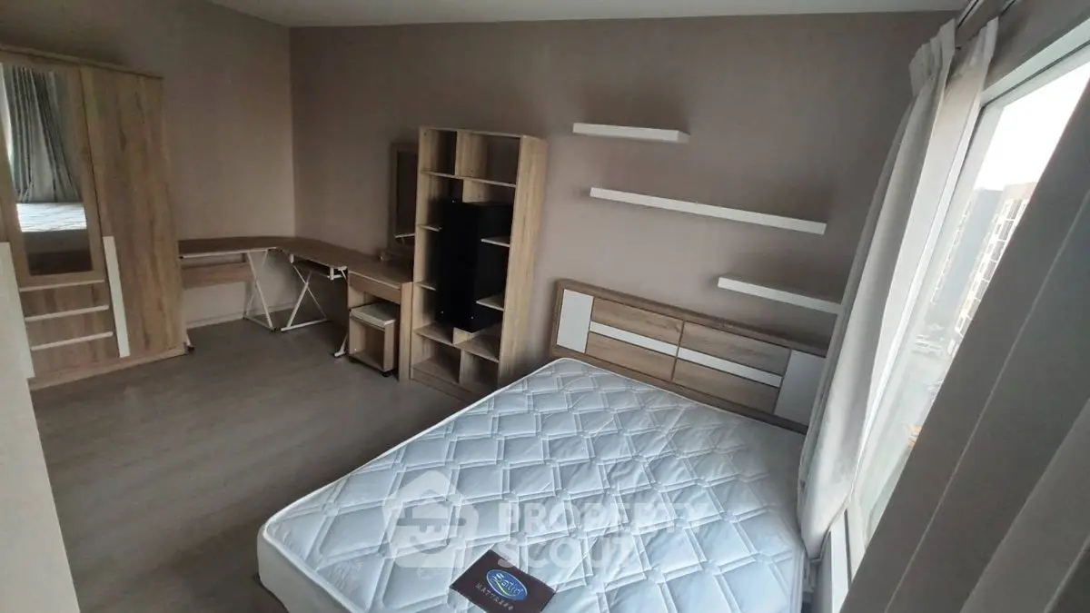 Modern bedroom with sleek furniture and large window offering natural light.