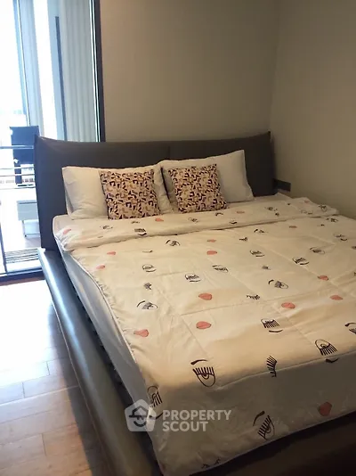 Cozy bedroom with modern decor and large bed near a balcony with natural light.