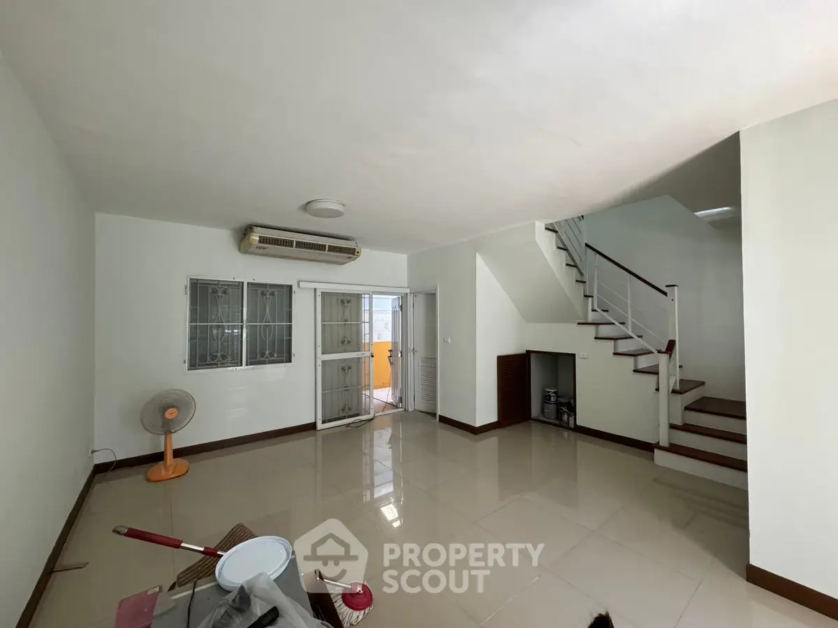 Spacious living room with staircase and air conditioning in modern home