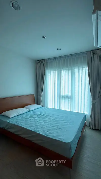 Spacious bedroom with large window and elegant curtains in modern apartment.