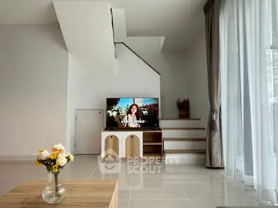 Modern living room with TV, staircase, and elegant decor in a bright, spacious interior.
