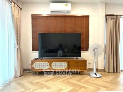 Modern living room with large TV, stylish wooden cabinet, and elegant curtains.