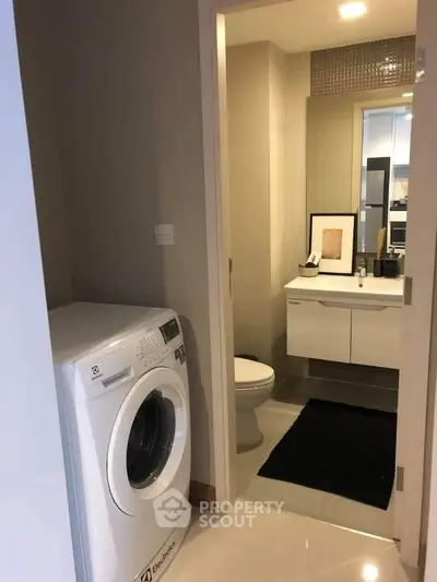 Modern bathroom with washing machine and sleek vanity in compact space.