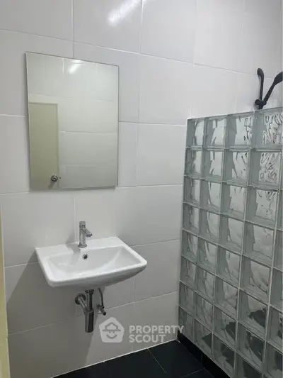 Modern bathroom with glass block shower and sleek white sink.