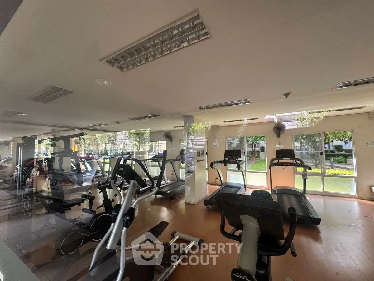 Spacious gym with modern equipment and large windows offering garden views.