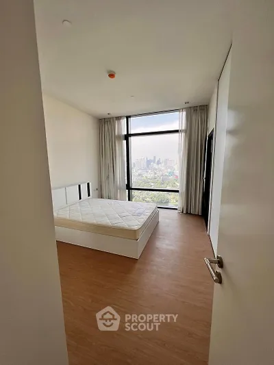 Spacious bedroom with city view and large window, featuring a comfortable bed and modern design.
