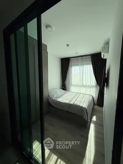 Cozy bedroom with modern decor and natural light through large window.
