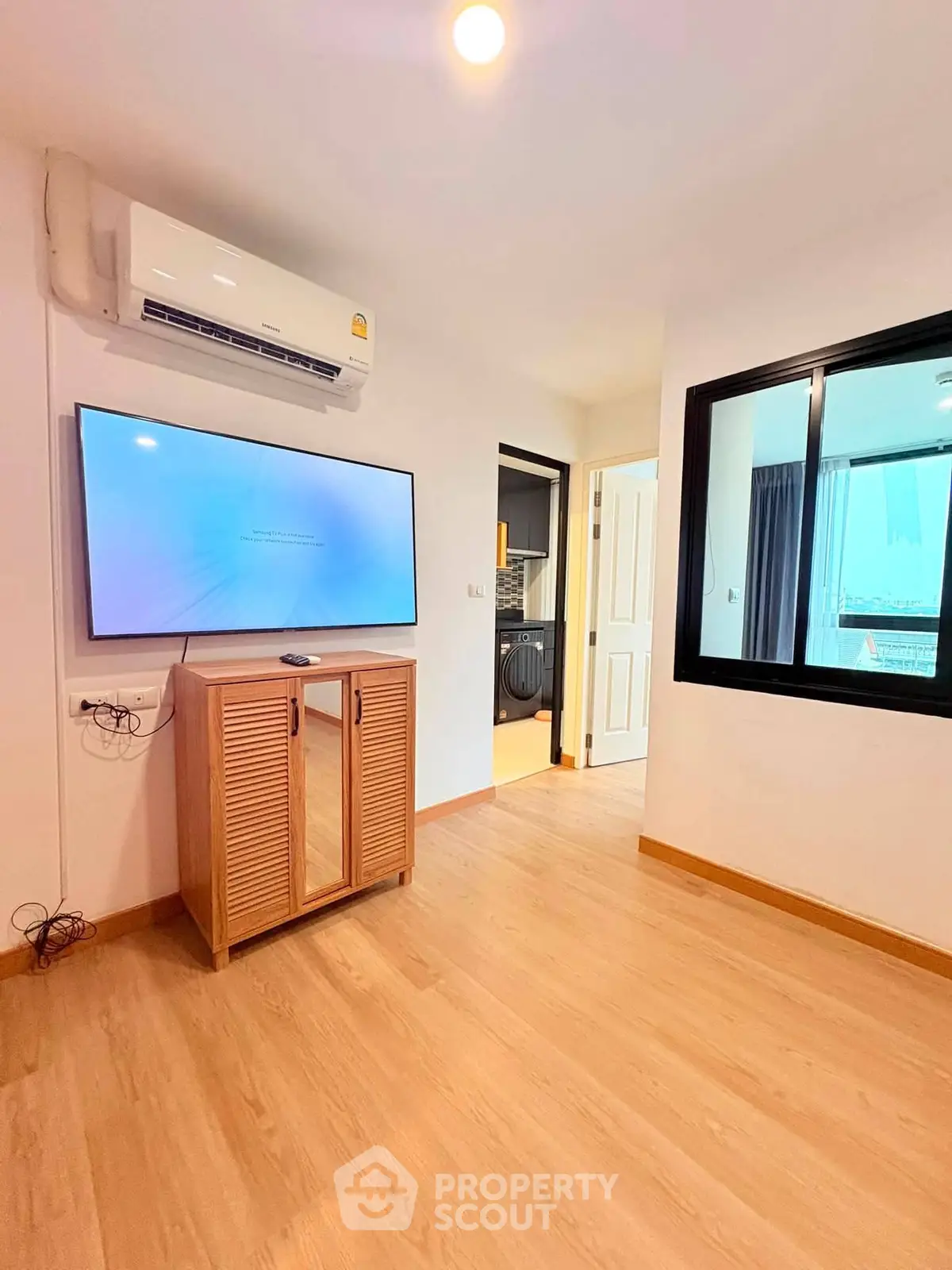 Modern living room with air conditioning and wall-mounted TV, featuring wooden flooring and sleek design.